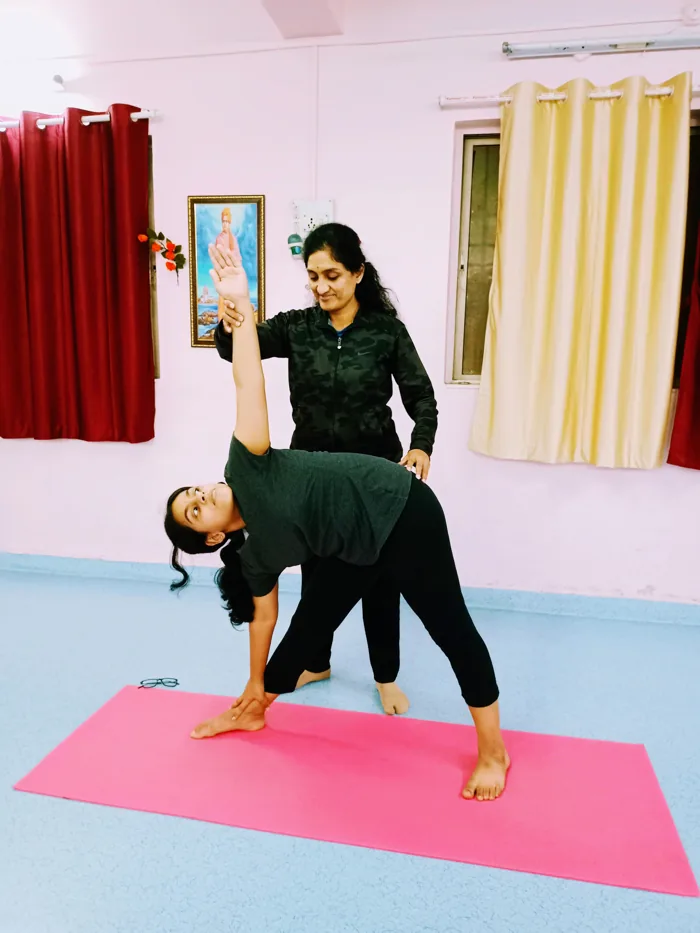 Dr. Manisha personally guiding a student through a standing yoga posture