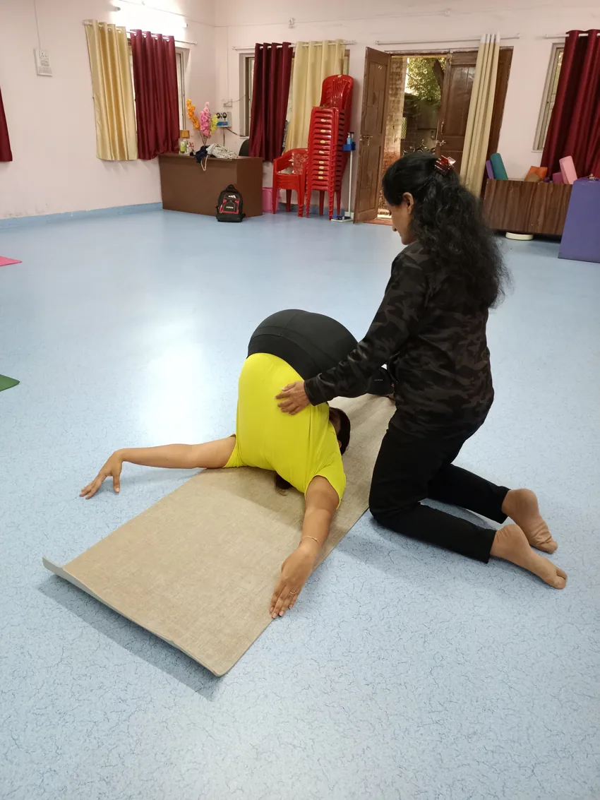 Dr. Manisha guiding a student through a supported floor stretch