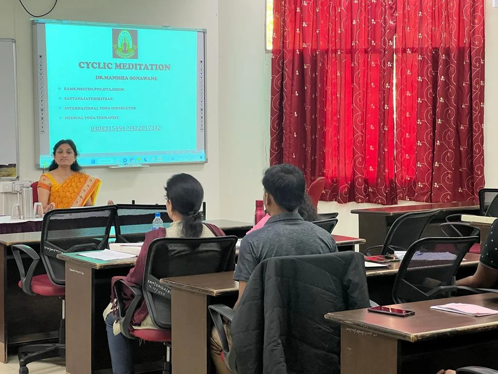 Dr. Manisha teaching yogic science to a group in a classroom